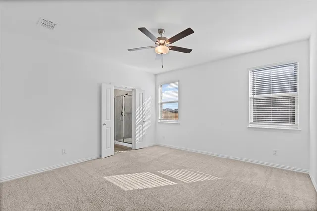 a view of a livingroom with a ceiling fan & windows