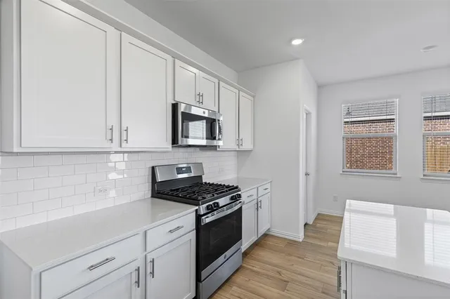 a kitchen with white cabinets a sink and appliances