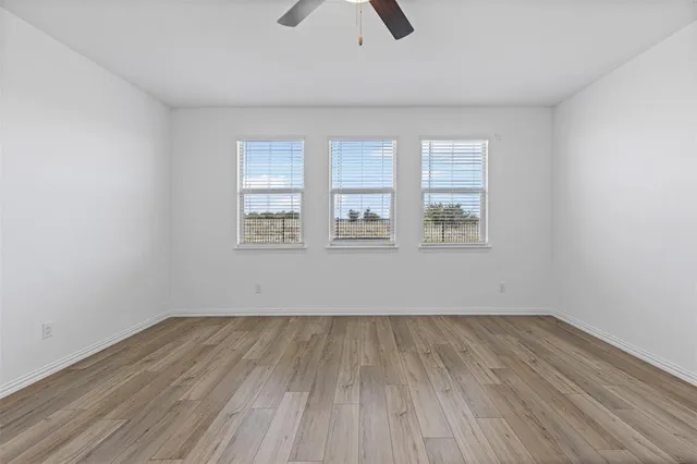 an empty room with wooden floor and windows