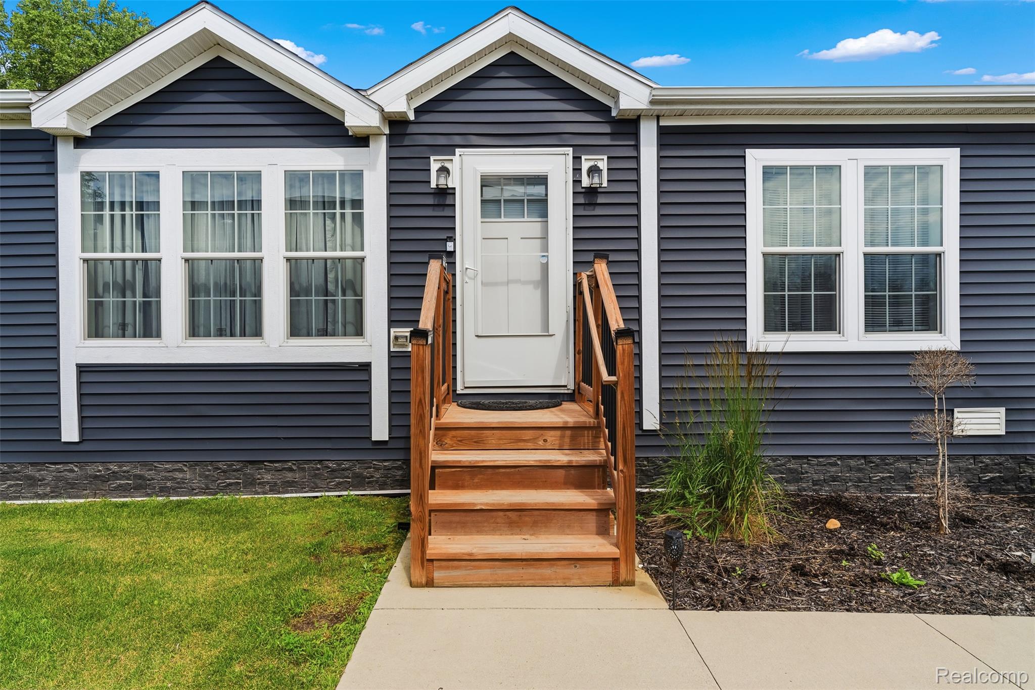 6450 Prince Boulevard Fenton, MI 48430 - Photo 2 of 31 Inviting front entrance featuring a wood staircase, white entry door with upper glass panel, and dark blue horizontal siding