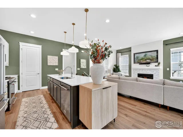 a kitchen with a counter top space a sink appliances and a living room view