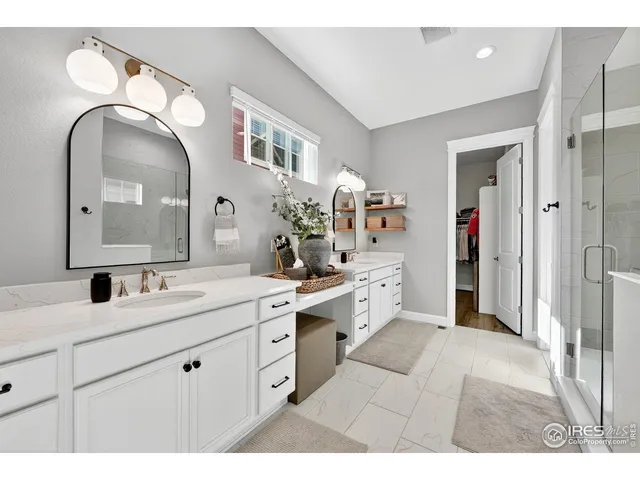 a spacious bathroom with a double vanity sink a mirror and a shower
