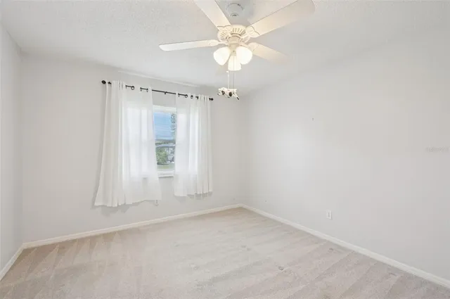 an empty room with a chandelier fan and windows