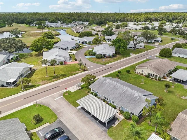 an aerial view of a residential houses with outdoor space and trees
