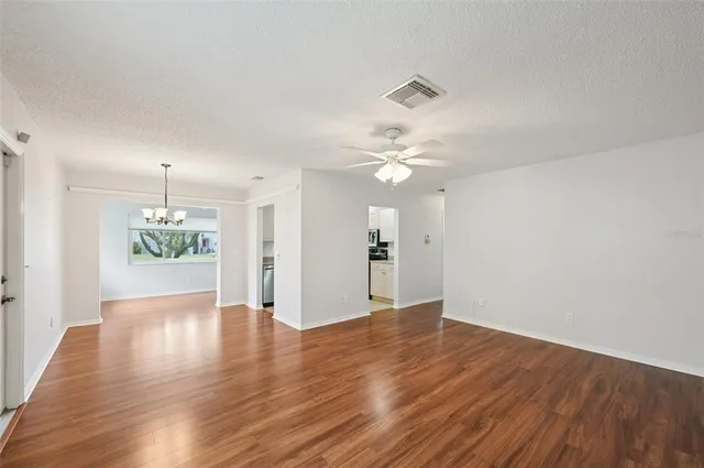 a view of an empty room with wooden floor and a ceiling fan