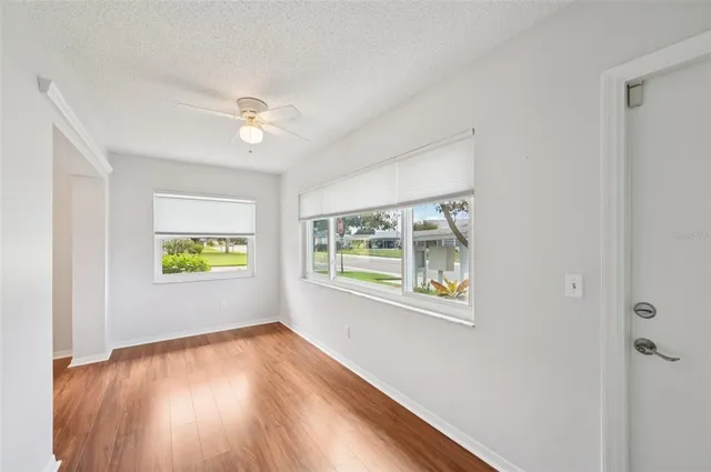 a view of an empty room with a window and wooden floor