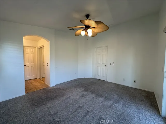 an empty room with closet and a chandelier fan