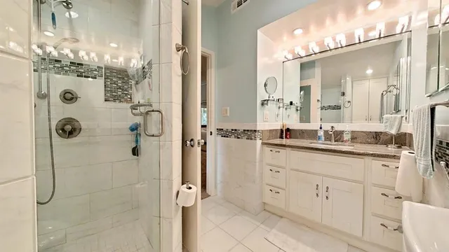 a bathroom with a granite countertop shower sink and white cabinets