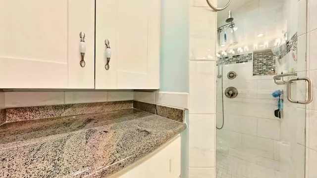 a bathroom with a granite countertop shower sink and mirror