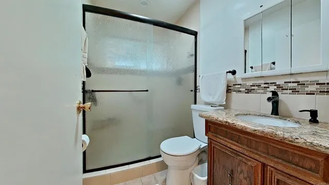 a bathroom with a granite countertop sink toilet and shower