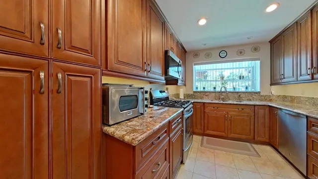 a kitchen with granite countertop stainless steel appliances a stove sink and cabinets