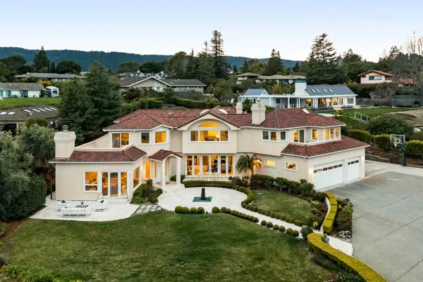 a view of a house with a big yard plants and large trees