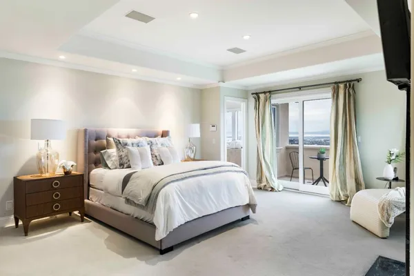 a spacious bedroom with a bed and a flat tv screen