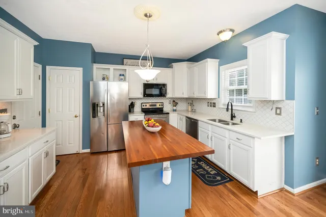 a kitchen with stainless steel appliances kitchen island granite countertop a sink stove and refrigerator
