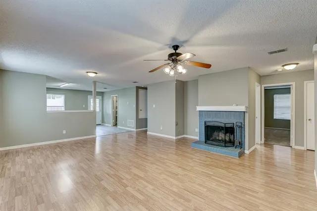 a view of an empty room with wooden floor fireplace and a window