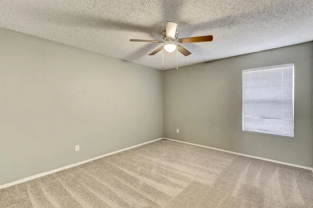 an empty room with a window and a fan