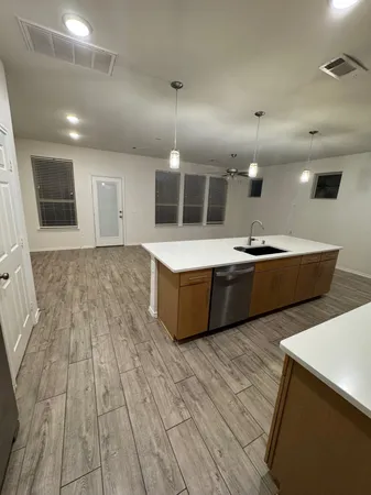 a large kitchen with stainless steel appliances a large counter top a sink a stove a refrigerator and cabinets