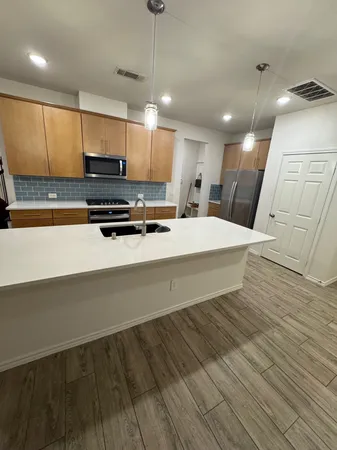 a large kitchen with stainless steel appliances a large counter top a stove a chimney a sink and a refrigerator