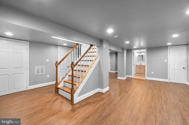 a view of an empty room with wooden floor stairs and a way to kitchen