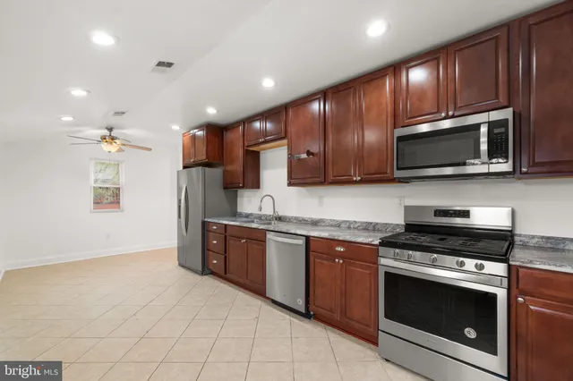 a kitchen with stainless steel appliances granite countertop wooden cabinets a stove top oven a sink and dishwasher
