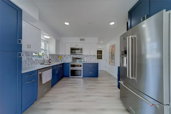 a large kitchen with stainless steel appliances kitchen island granite countertop a refrigerator and a stove top oven