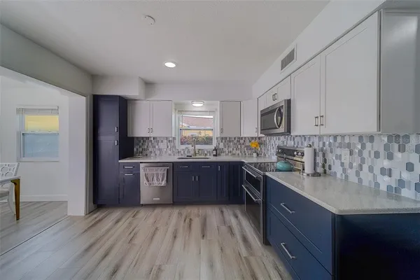 a kitchen with stainless steel appliances granite countertop wooden cabinets a stove top oven a sink and dishwasher with wooden floor