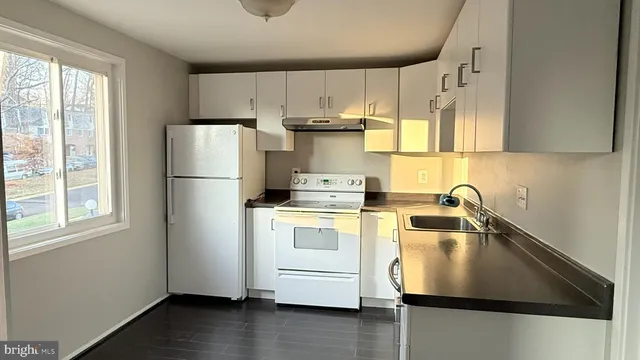 a kitchen with kitchen island a sink a refrigerator and white cabinets