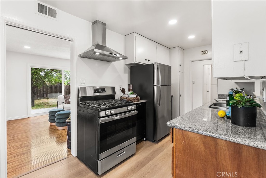 13361 Roxey Drive Garden Grove, CA 92843 - Photo 7 of 31 a kitchen with stainless steel appliances granite countertop a refrigerator a stove and a wooden floors