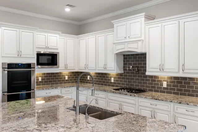 a kitchen with granite countertop a stove a sink and a microwave