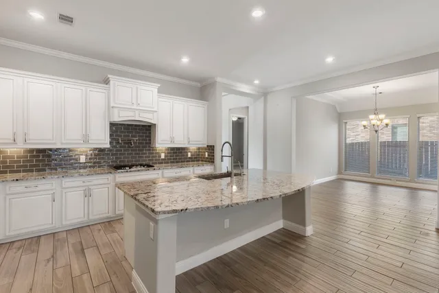 a kitchen with stainless steel appliances granite countertop a sink stove and white cabinets with wooden floor