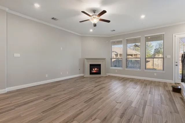 a view of an empty room with a window and wooden floor
