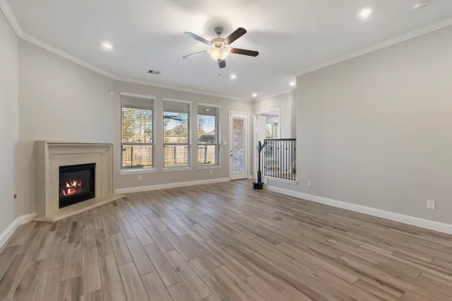 an empty room with wooden floor fireplace and windows