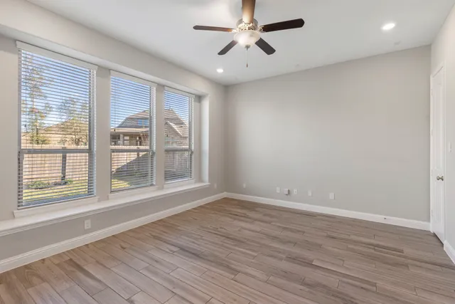 a view of an empty room with a window and wooden floor