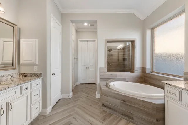 a bathroom with a granite countertop sink and mirror with bathtub