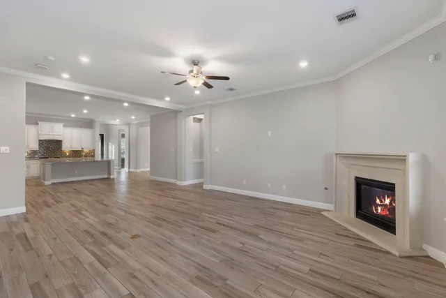 a view of an empty room with wooden floor and a fireplace