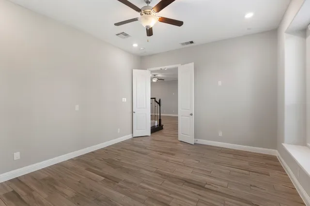 an empty room with wooden floor and a ceiling fan