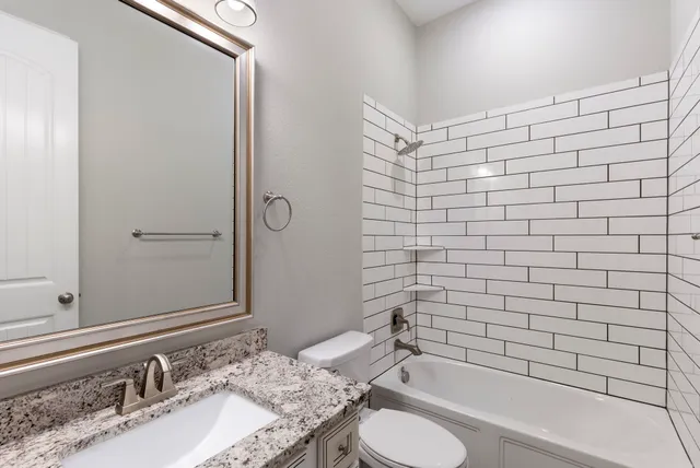 a bathroom with a granite countertop sink toilet and shower
