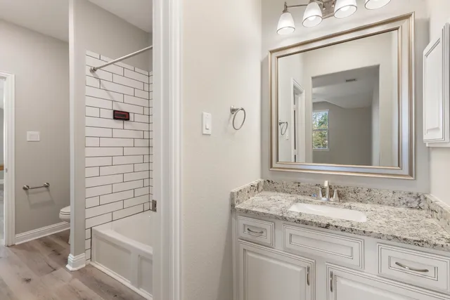 a bathroom with a granite countertop sink a mirror and a bathtub