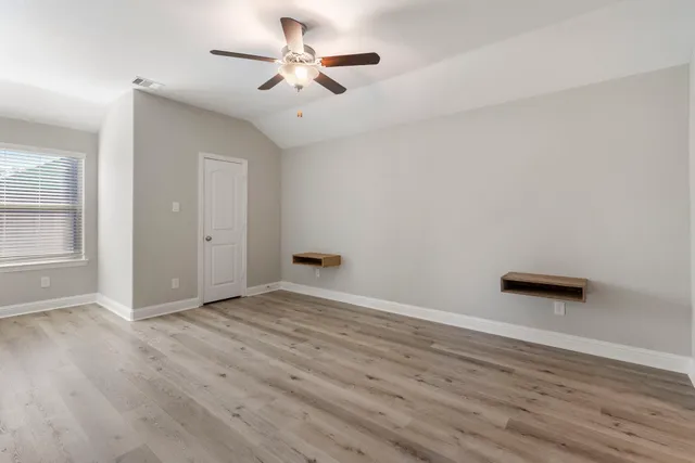 an empty room with wooden floor and windows