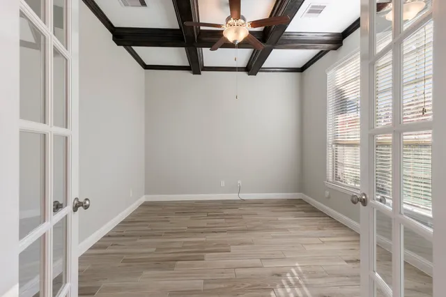 a view of an empty room with wooden floor and windows