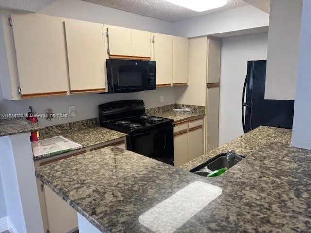 a kitchen with stainless steel appliances granite countertop a stove top oven a sink a refrigerator white cabinets and wooden floor