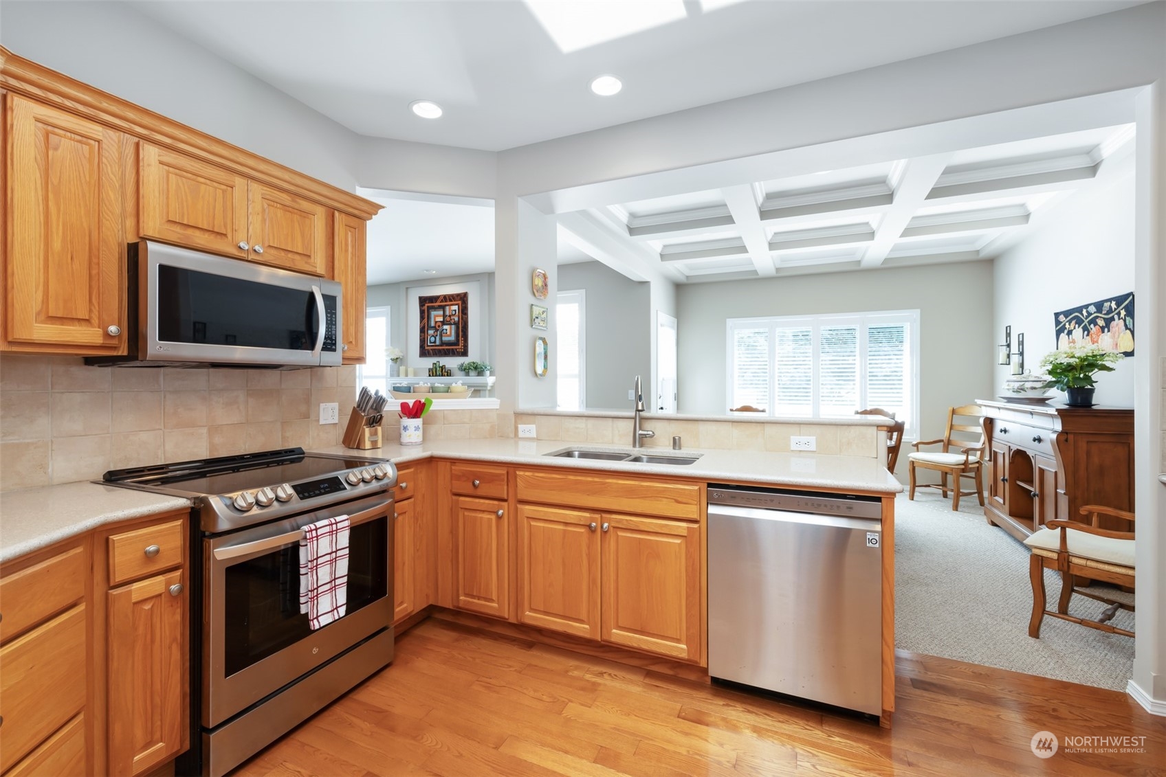 431 Blakely Boulevard Sequim, WA 98382 - Photo 12 of 34 a kitchen with stainless steel appliances granite countertop a stove top oven a sink dishwasher a dining table and chairs with wooden floor