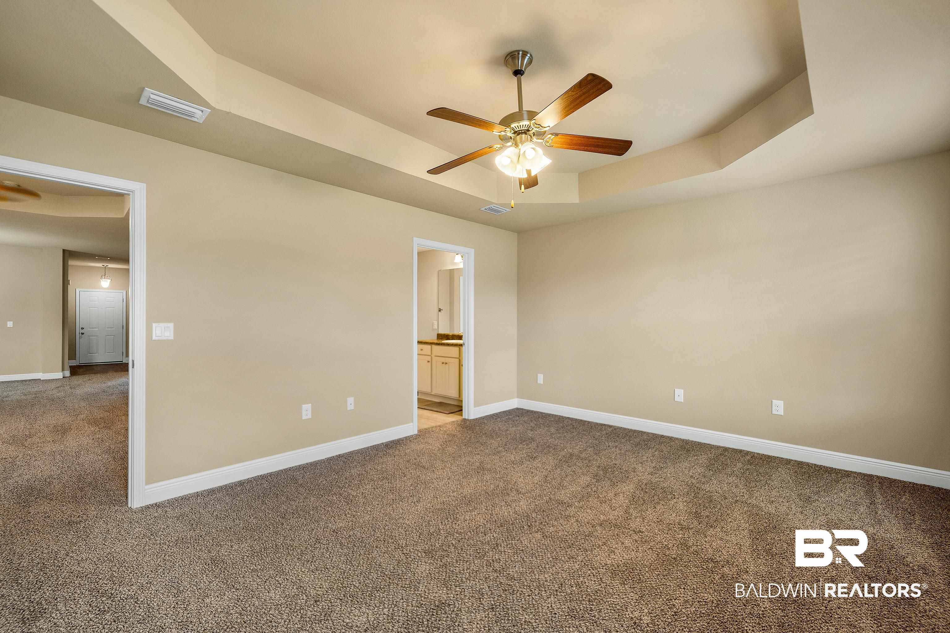 22631 Lake South Drive Foley, AL 36535 - Photo 12 of 25 Unfurnished bedroom with a tray ceiling, ceiling fan, ensuite bathroom, and carpet floors