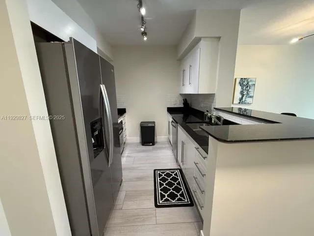 a kitchen with a sink a refrigerator a stove and white cabinets