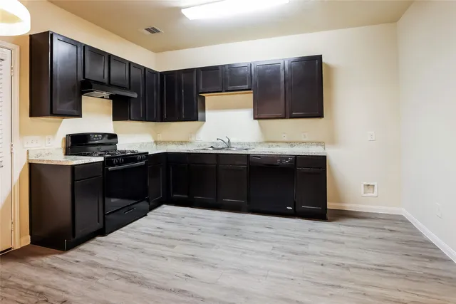 a kitchen with stainless steel appliances granite countertop wooden cabinets a stove top oven and sink