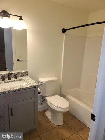 a bathroom with a granite countertop toilet sink and mirror