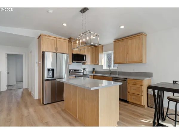 a kitchen with kitchen island granite countertop a sink cabinets and stainless steel appliances