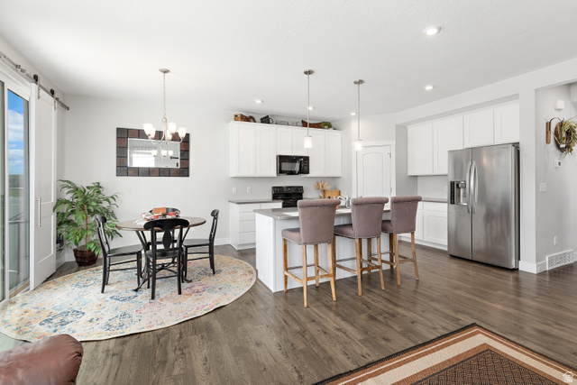 2343 Wysteria Drive Mapleton, UT 84664 - Photo 10 of 30 Kitchen with black appliances, white cabinetry, a kitchen breakfast bar, and a kitchen island