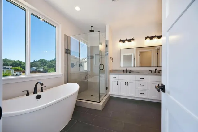a spacious bathroom with a double vanity sink a mirror a bathtub and shower