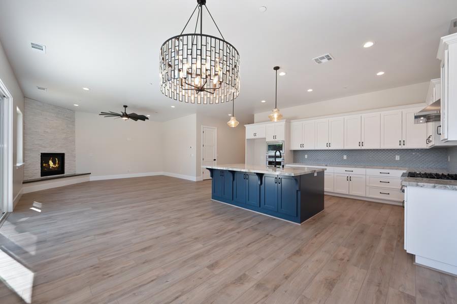 3301 Stone Field Way Loomis, CA 95650 - Photo 9 of 33 a large kitchen with stainless steel appliances granite countertop a large stove a sink dishwasher and a fireplace with wooden floor